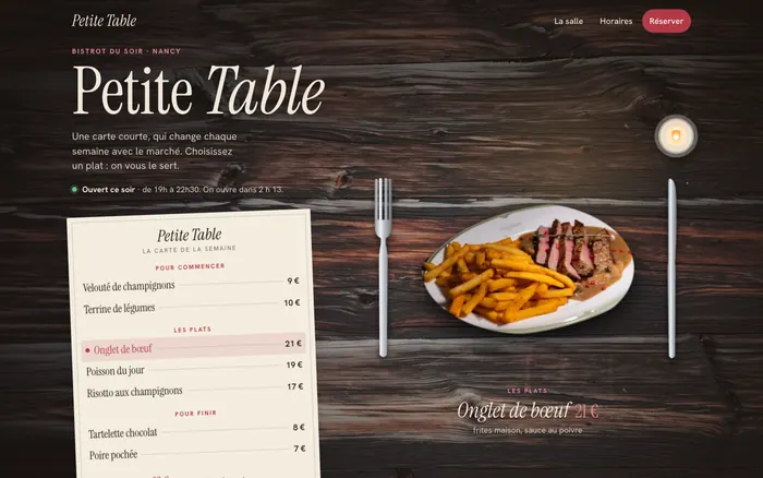 La table en bois du bistrot le soir, la carte en papier et une assiette servie entre la fourchette et le couteau, vu sur ordinateur